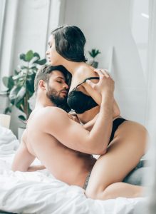 A man pulls a woman's bra down as he kisses her skin