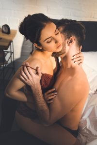 A man kissing a woman and taking off her bra